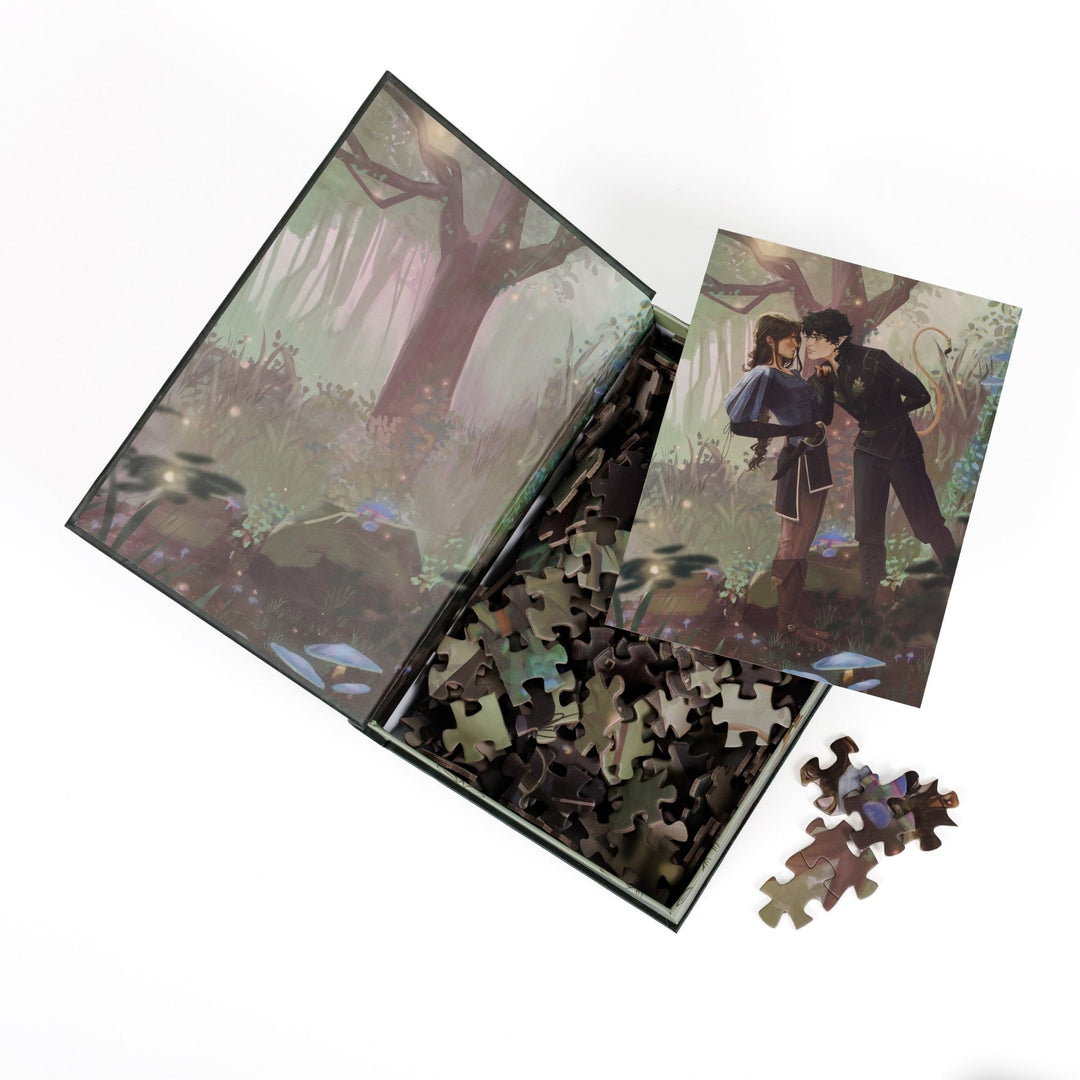 An open book-shaped box reveals puzzle pieces. Art on the inner flap of green forest. An art print of Jude and Cardan atop the pieces.