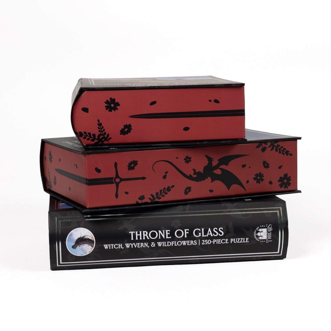 Stack of 3 puzzle boxes showing all sides. Red edges with black swords & wyverns and the spine of the box: Witch, Wyvern & Wildflowers Throne of Glass 250-piece puzzle.
