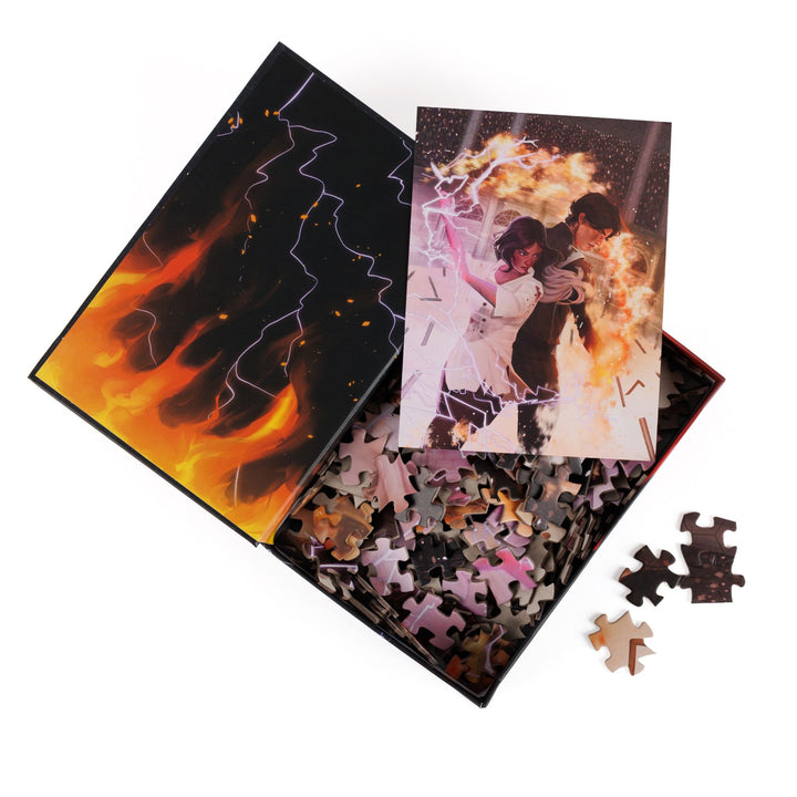 An open book-shaped box reveals puzzle pieces. Inner art on the top flap of flames and lightning. An art print of Mare and Cal wielding magic atop the pieces.