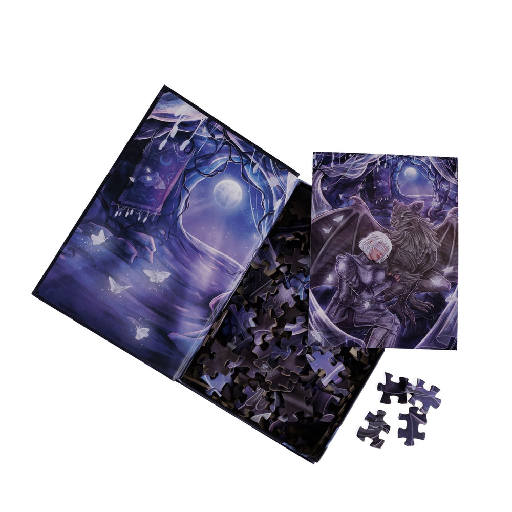 An open book-shaped box reveals puzzle pieces. Inner art on the top flap moonlit cavern with moths. An art print of Sybil and Bartholomew atop the pieces.