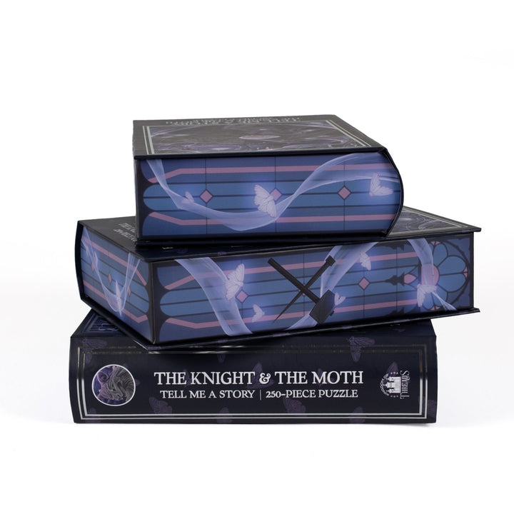 Stack of 3 puzzle boxes showing all sides. Blue & pink stained glass with silk moth accents and the spine of the box reads Tell Me a Story The Knight & the Moth 250-piece puzzle.
