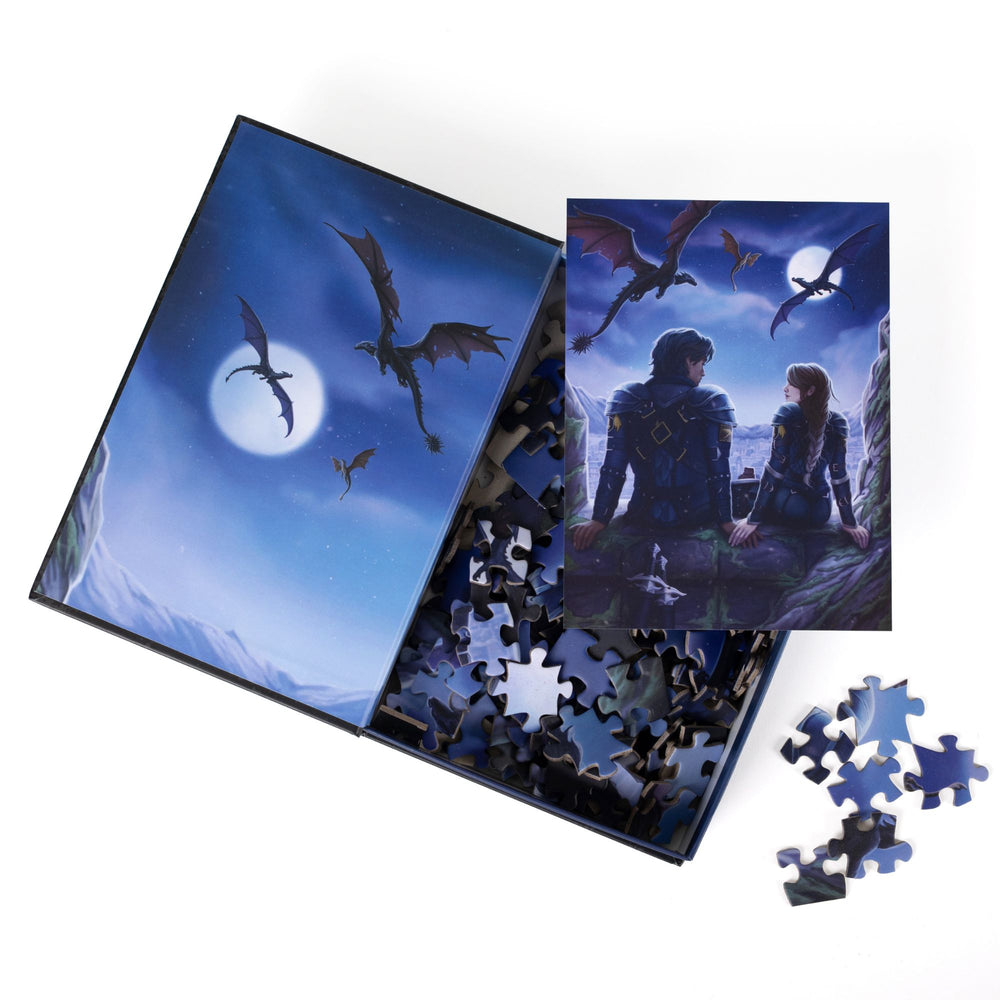 An open book-shaped box reveals puzzle pieces. Inner art on the top flap of three dragons flying. An art print of Xaden and Violet atop the pieces.