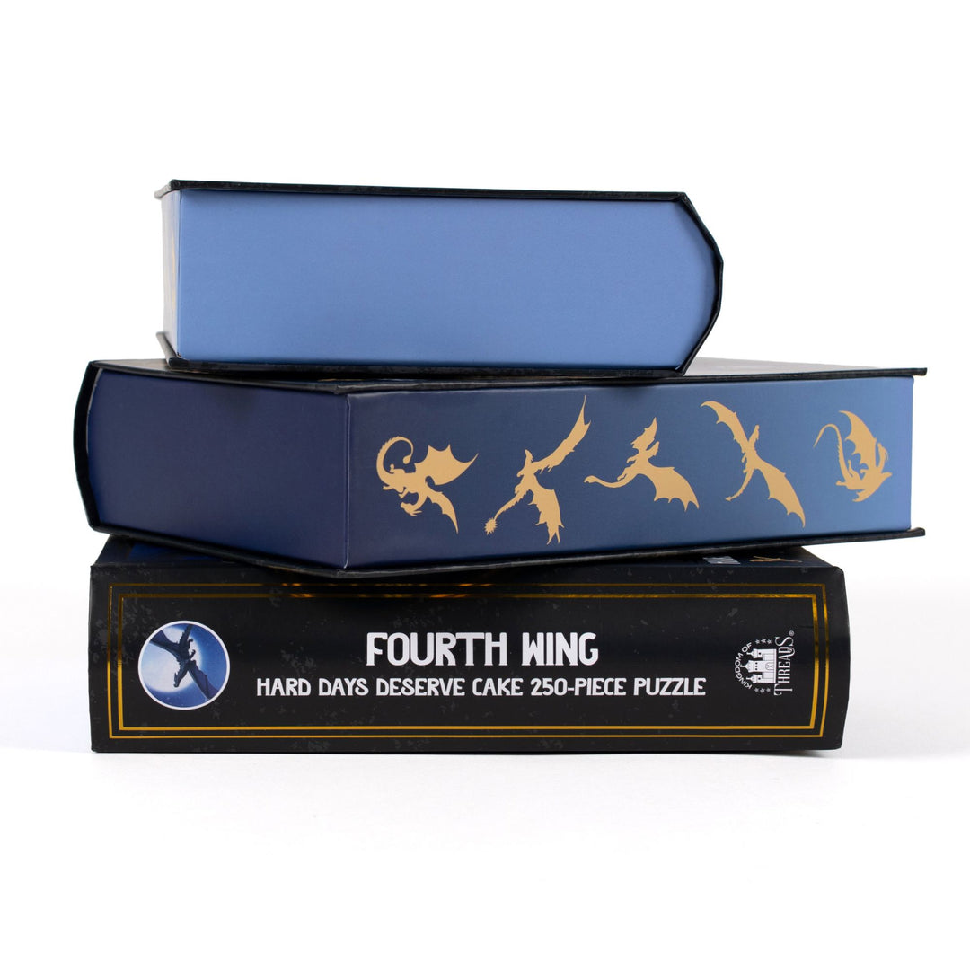 Stack of 3 puzzle boxes showing all sides. Blue edges with gold dragon out. The spine of the box reads Fourth Wing Hard Days Deserve Cake 250-piece puzzle.