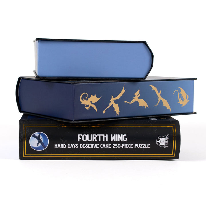 Stack of 3 puzzle boxes showing all sides. Blue edges with gold dragon out. The spine of the box reads Fourth Wing Hard Days Deserve Cake 250-piece puzzle.