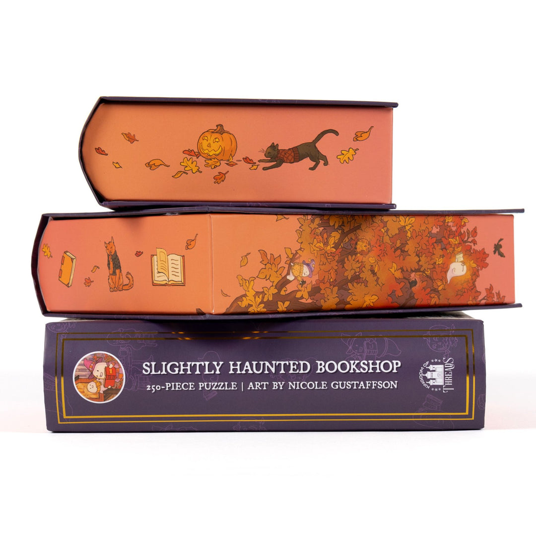 Stack of 3 puzzle boxes showing all sides. Orange edges with ghosts, books, and cats. The spine of the box reads Slightly Haunted Bookshop 250-piece puzzle, art by Nicole Gustafsson.