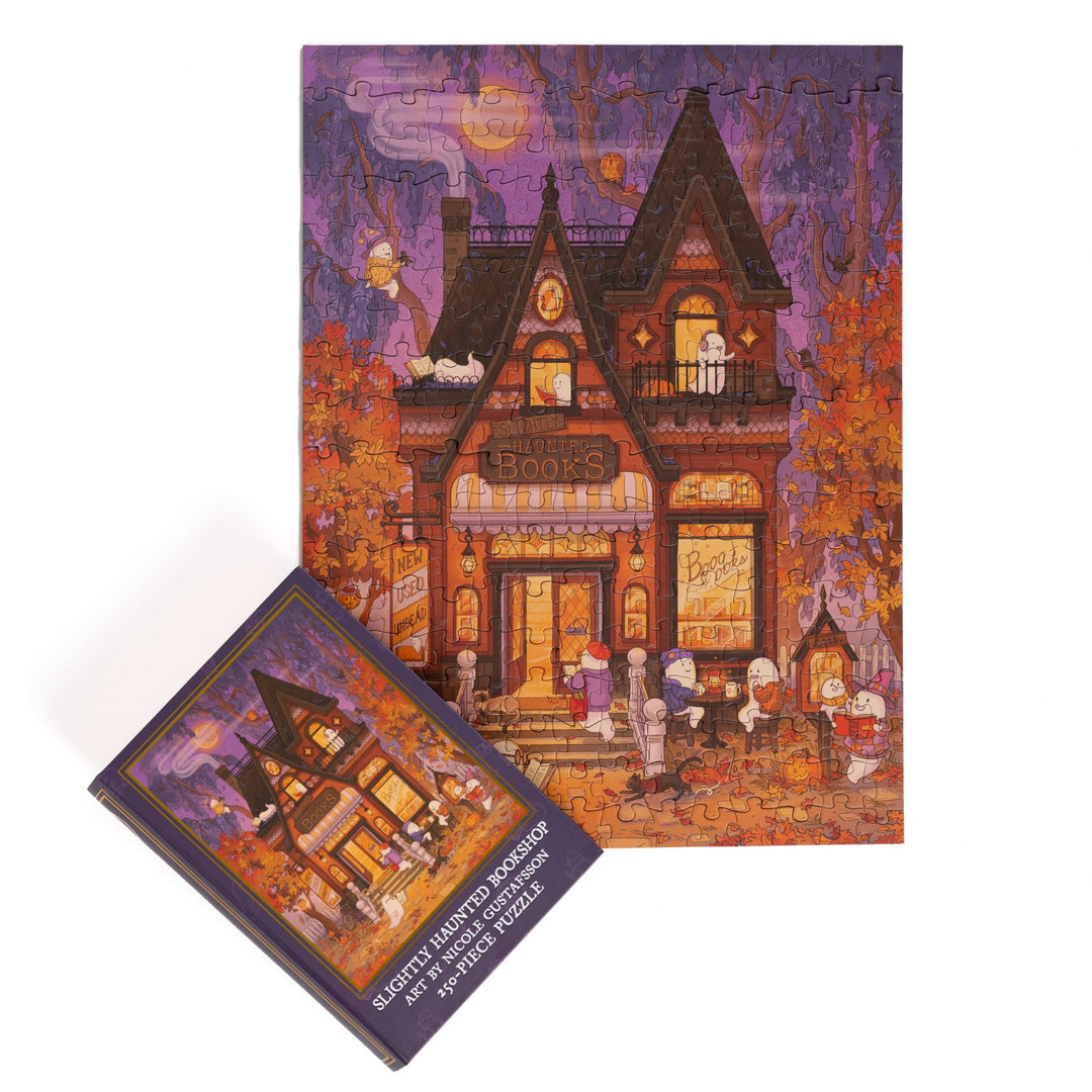 Completed puzzle of cozy haunted bookshop and purple, book-shaped box with matching art for Slightly Haunted Bookshop 250-piece puzzle.