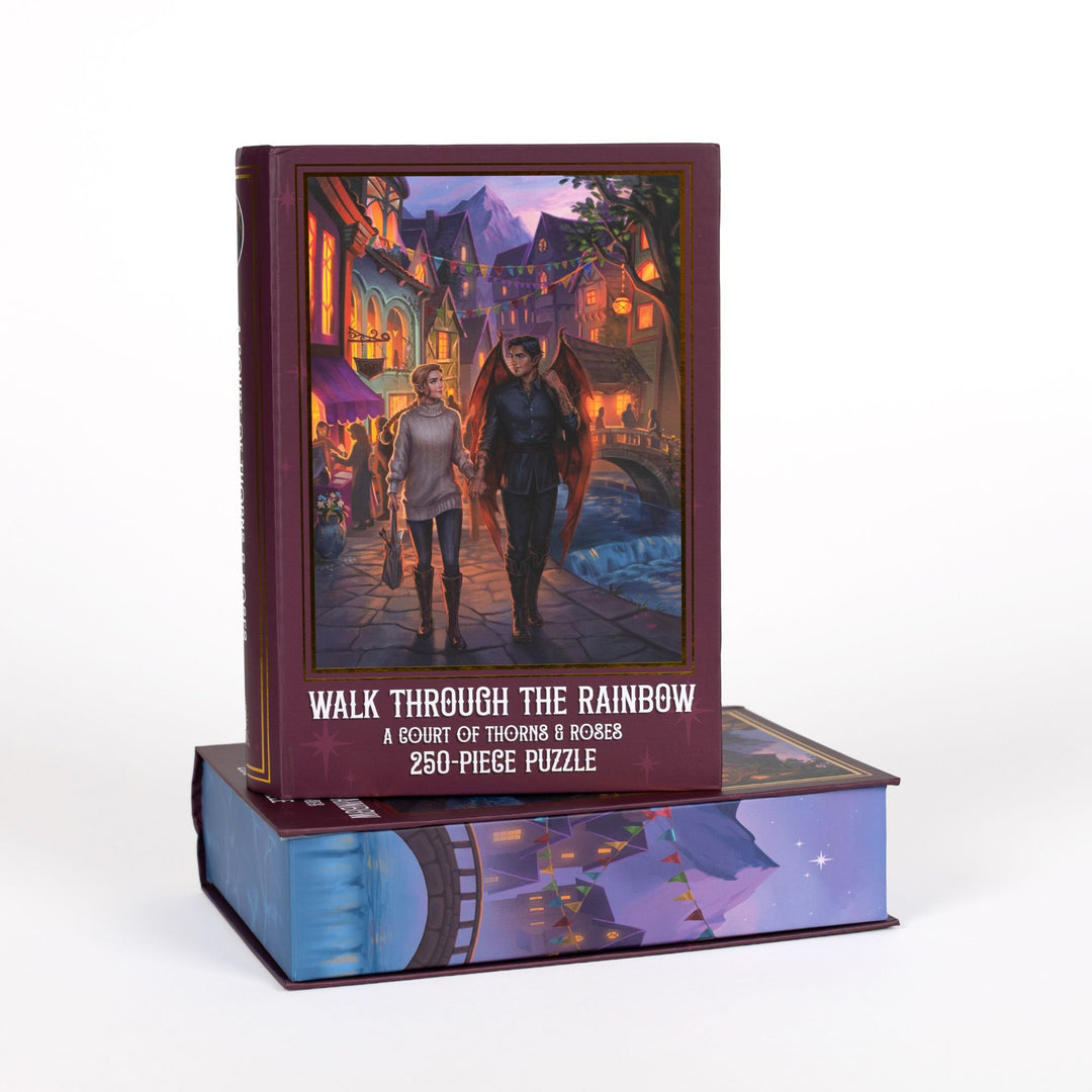 Book-shaped purple box for Walk Through the Rainbow, A Court of Thorns and Roses 250-piece puzzle. Art on the front is of Feyre and Rhys walking hand in hand on a city street.
