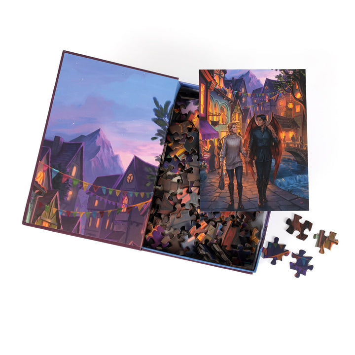 An open book-shaped box reveals puzzle pieces. Inner art on the top flap of Velaris’ Rainbow district. An art print of Feyre and Rhys atop the pieces.