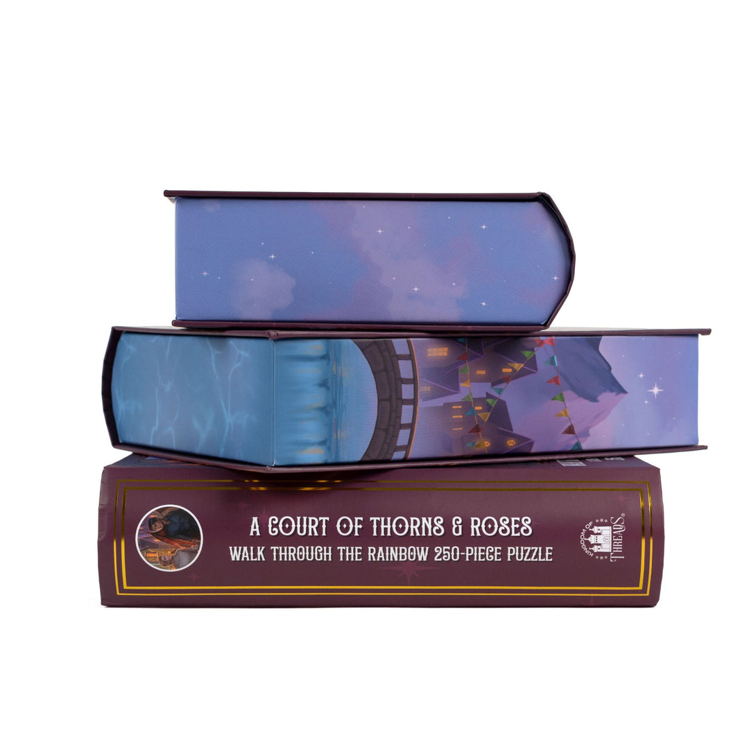 Stack of 3 puzzle boxes showing all sides. Blue edges with a scene of Velaris. The spine of the box reads A Court of Thorns and Roses, Walk Through the Rainbow 250-piece puzzle.