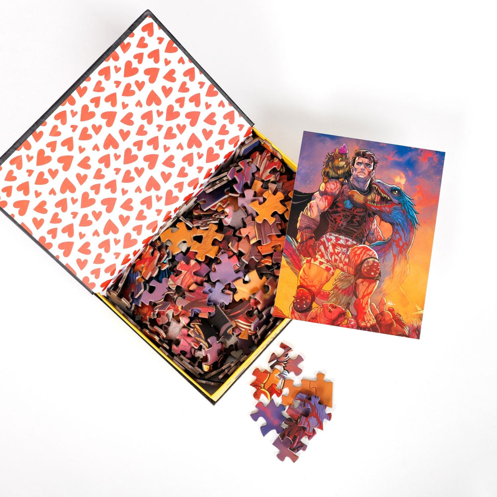 An open book-shaped box reveals puzzle pieces. Inner art on the top flap is a heart pattern on white. An art print of Carl, Princess Donut and Mongo atop the pieces.