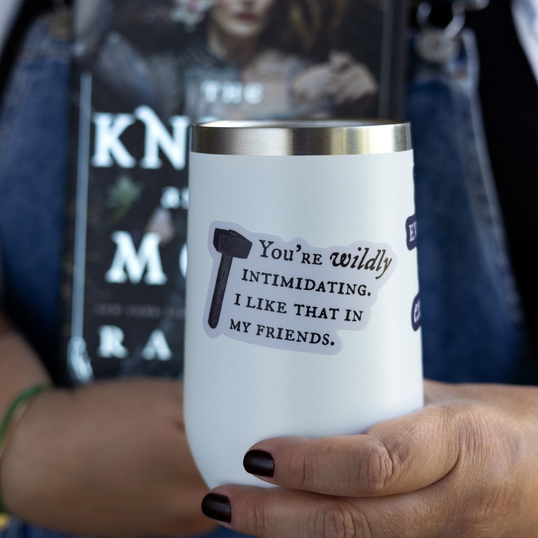Quote sticker from Knight and the Moth ‘You’re wildly intimidating. I like that in my friends’ on a white tumbler. Light purple sticker with dark text and a hammer.