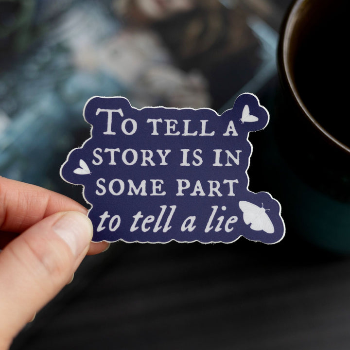 Quote sticker ‘To tell a story is to in some part tell a lie’ held over The Knight and the Moth. Dark purple sticker with white text.