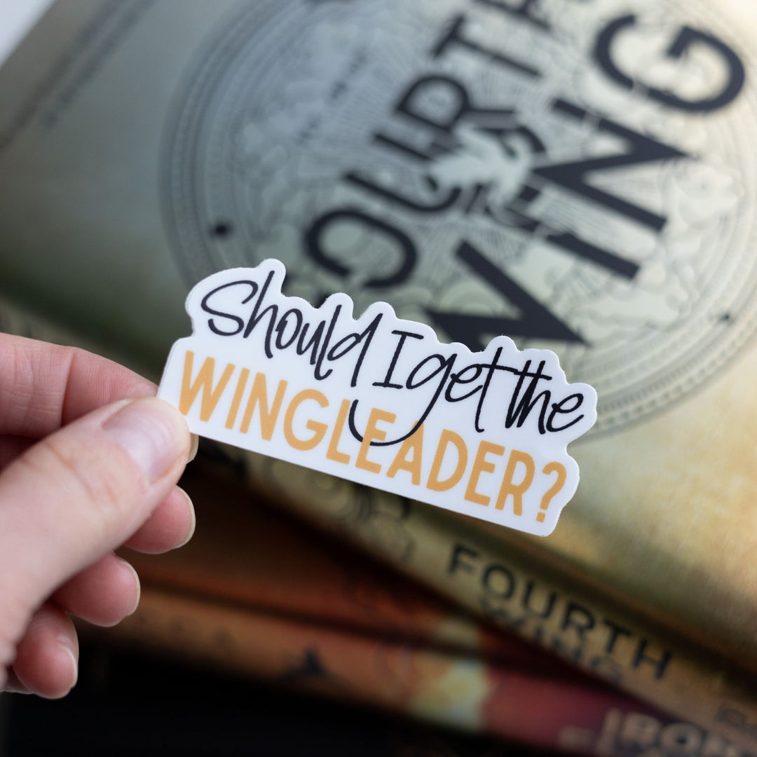  Fourth Wing quote sticker: ‘ Should I get the wingleader’ in black and gold colors, held over Fourth Wing.
