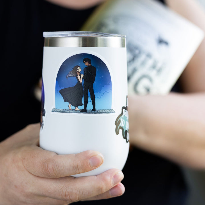 Sticker of Violet and Xaden, from Fourth Wing, on the parapet, gazing into each other's eyes. On a white tumbler.
