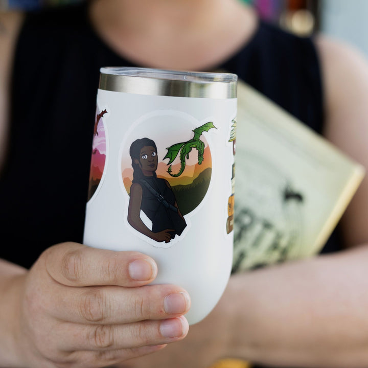 Sticker of Rhiannon in black riding leathers with her green dragon Feirge flying behind her. Characters from Fourth Wing. On a white tumbler.
