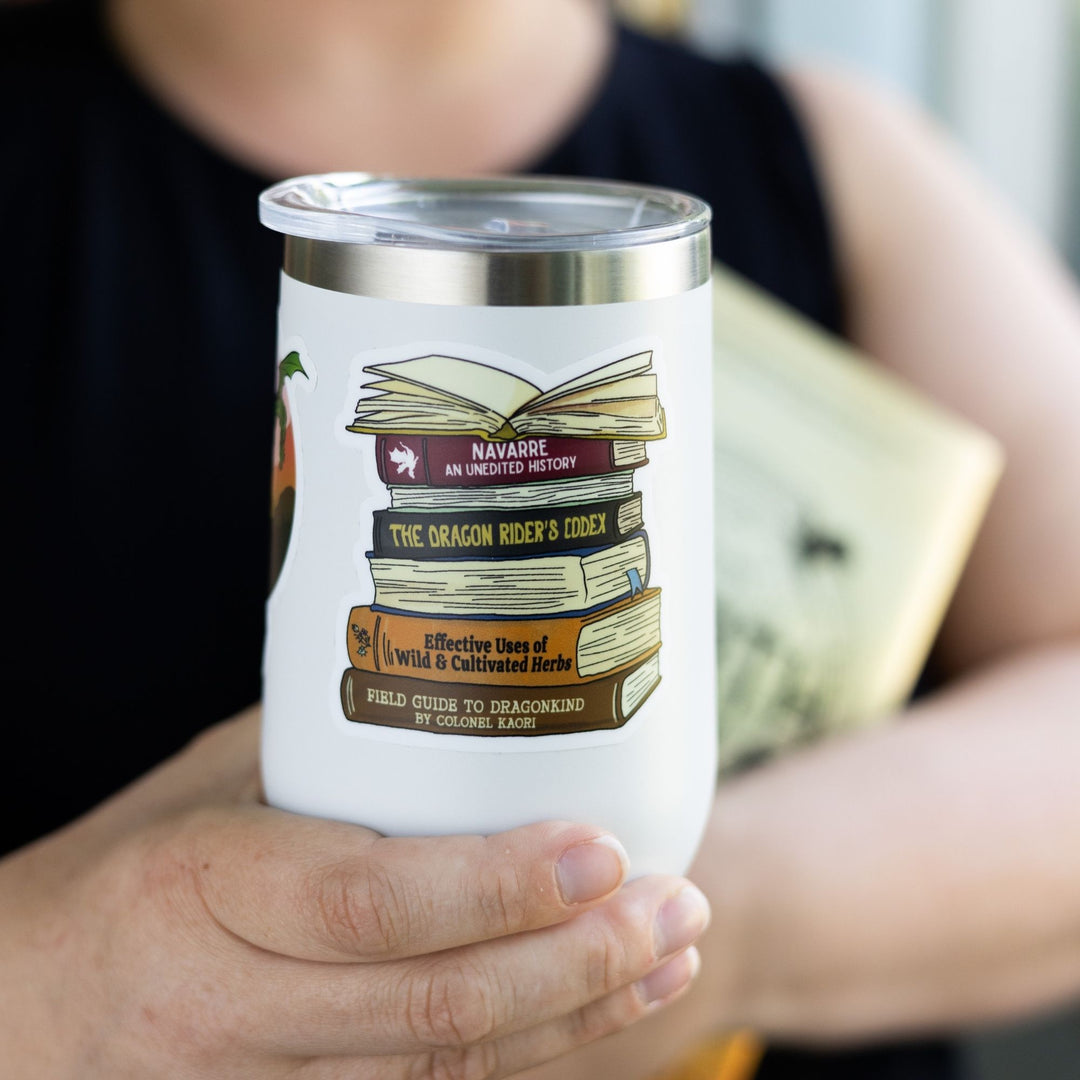 Sticker of a stack of books spines from Fourth Wing, like ‘Navarre: An Unedited History,’ and ‘The Dragon Rider’s Codex.’ On a white tumbler.
