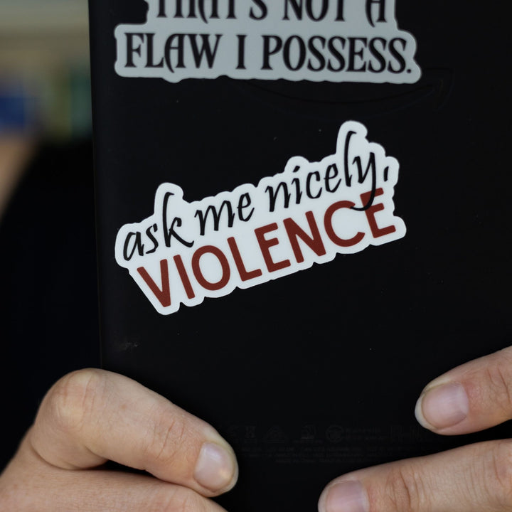 Fourth Wing quote sticker: ‘Ask me nicely, Violence’ in red and black letters. On a black e-reader.