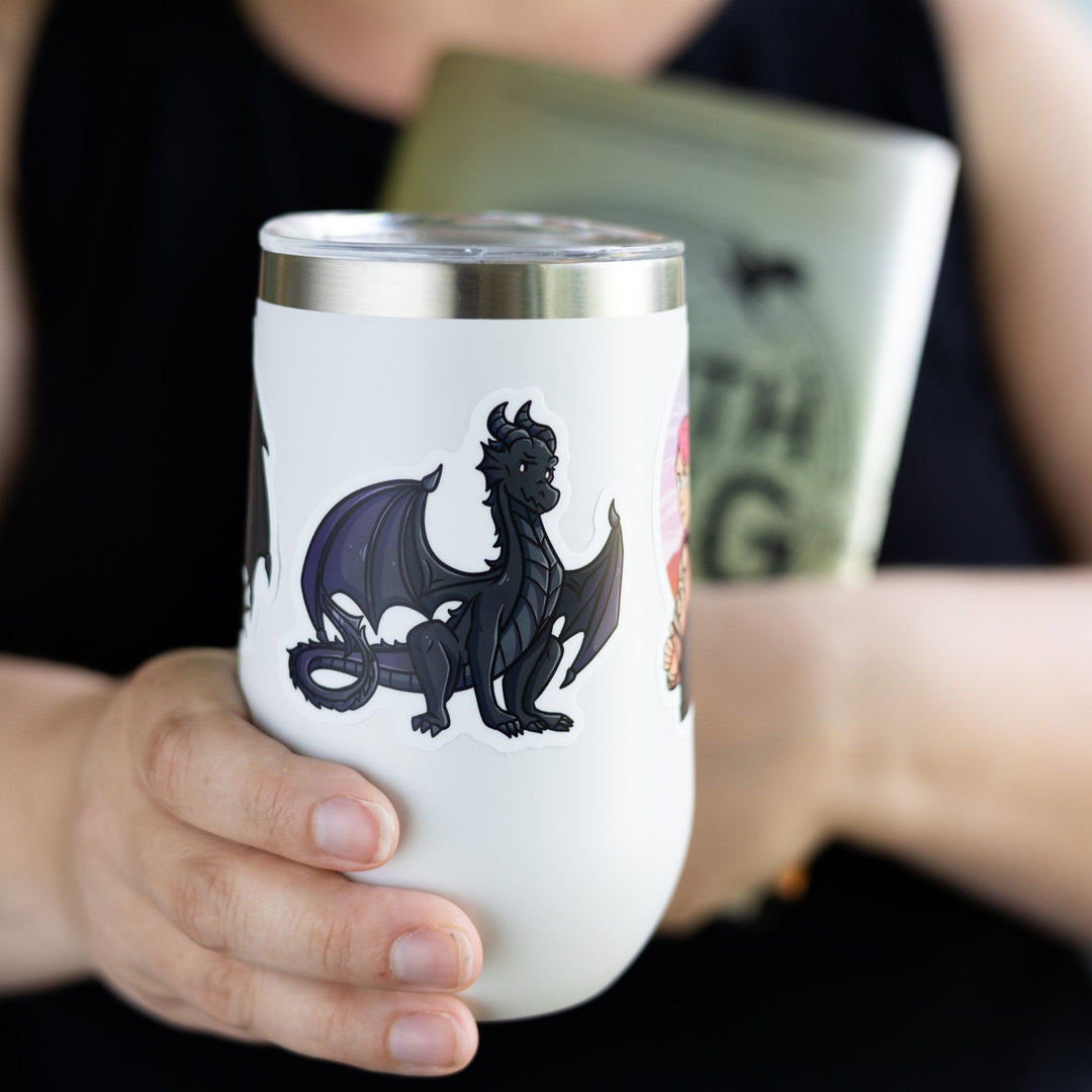 Sticker of a teenage Andarna, a black dragon who is sitting proudly, tail curled. On a white tumbler. Character from Fourth Wing.