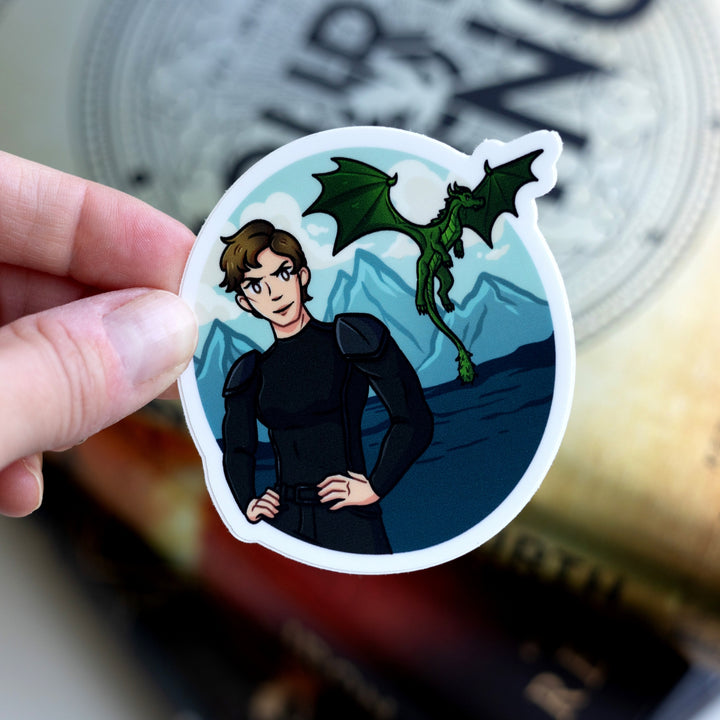 Sticker of Mira in black riding leathers with the sea, mountains, and a green dragon behind her. Held over Fourth Wing.