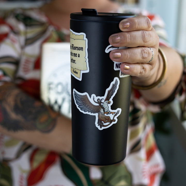 Sticker of Cat riding a griffin in brown riding leathers, a dagger raised above her head. On a black tumbler.