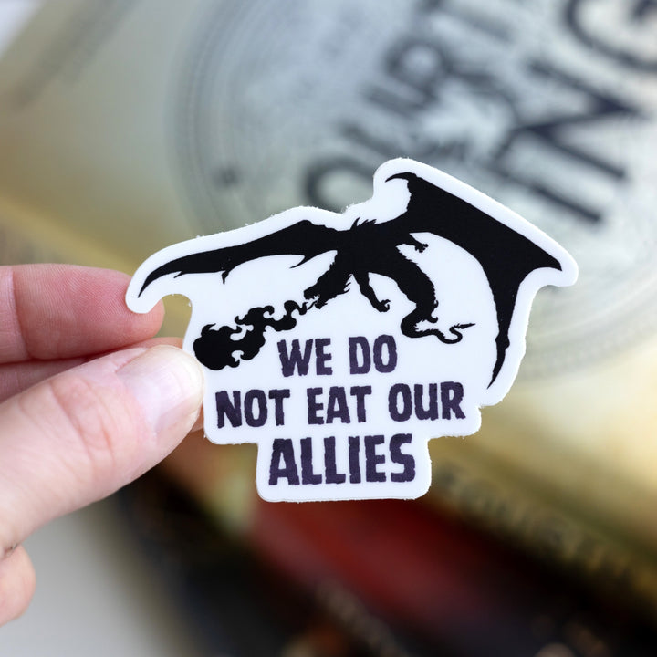 Sticker of a silhouette of a black dragon breathing fire. Below it reads ‘ We do not eat our allies. Held over Fourth Wing.