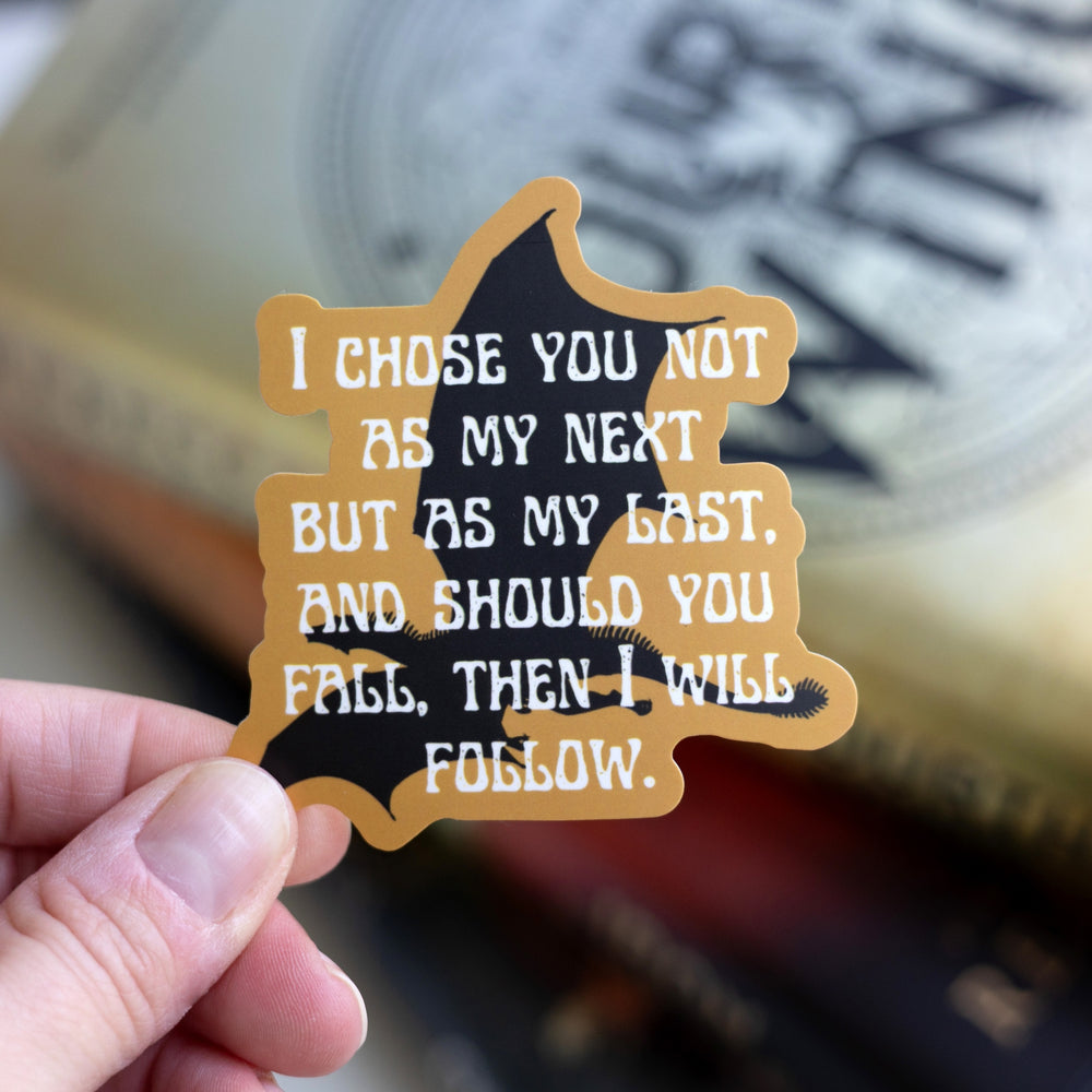Sticker of a black dragon on a gold background with the Fourth Wing quote: ‘I choose you not as my next but as my last, and should you fall then I will follow.’ Held over Fourth Wing.