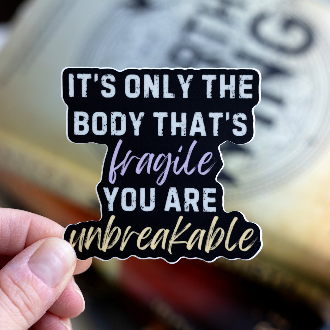  Fourth Wing quote sticker: ‘It’s only the body that’s fragile you are unbreakable.’ Words are light gray but ‘fragile’ is purple and ‘unbreakable’ is gold. Held over Fourth Wing.