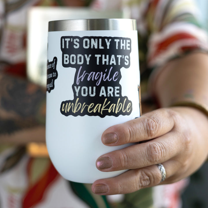 Fourth Wing quote sticker: ‘It’s only the body that’s fragile you are unbreakable.’ Words are light gray but ‘fragile’ is purple and ‘unbreakable’ is gold. On a white tumbler.