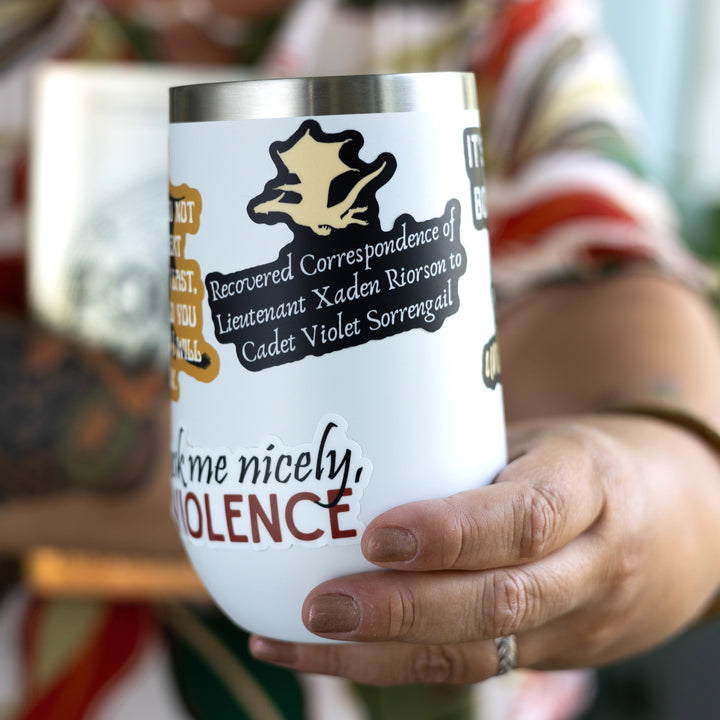 Sticker of a gold dragon flying over the words ‘Recovered correspondence of Lieutenant Xaden Riorson to Cadet Violet Sorrengail.’ On a white tumbler.
