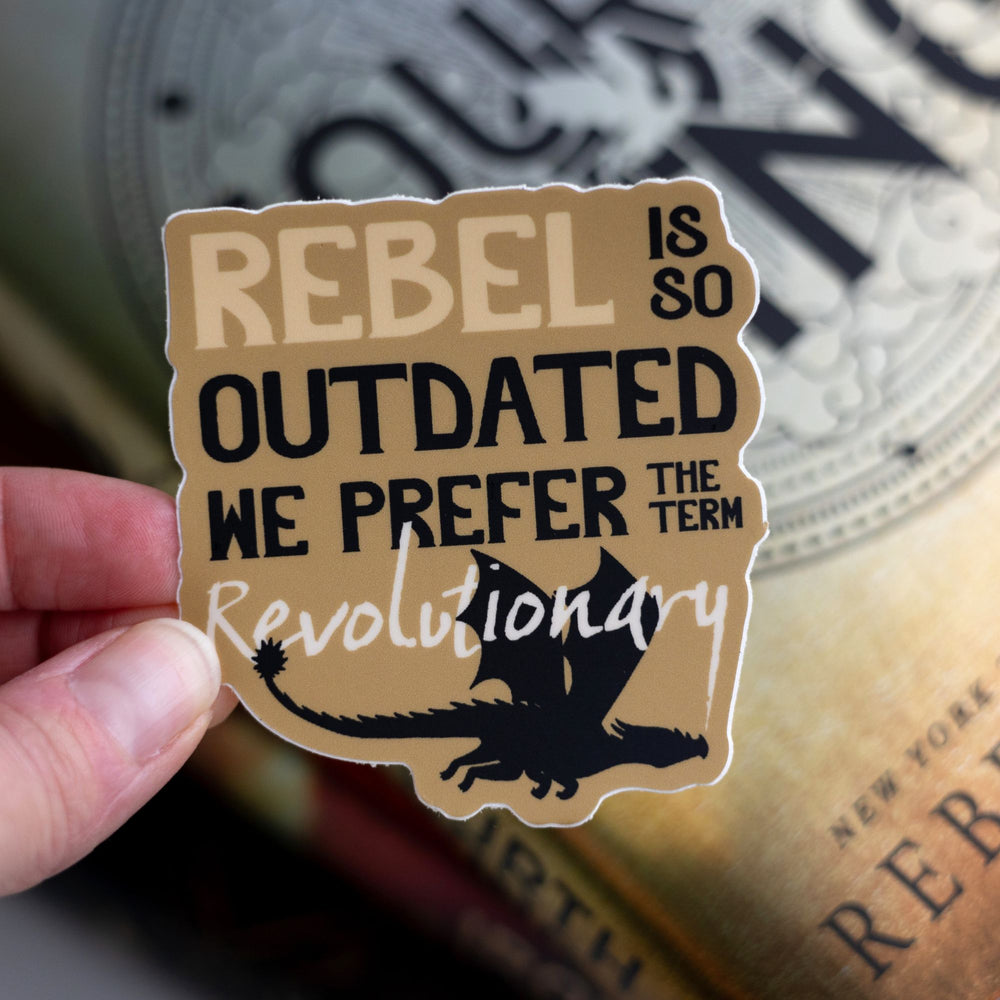 Sticker that reads ‘Rebel is so outdated we prefer the term revolutionary’. On a yellow background with a black dragon flying underneath. Held above Fourth Wing.
