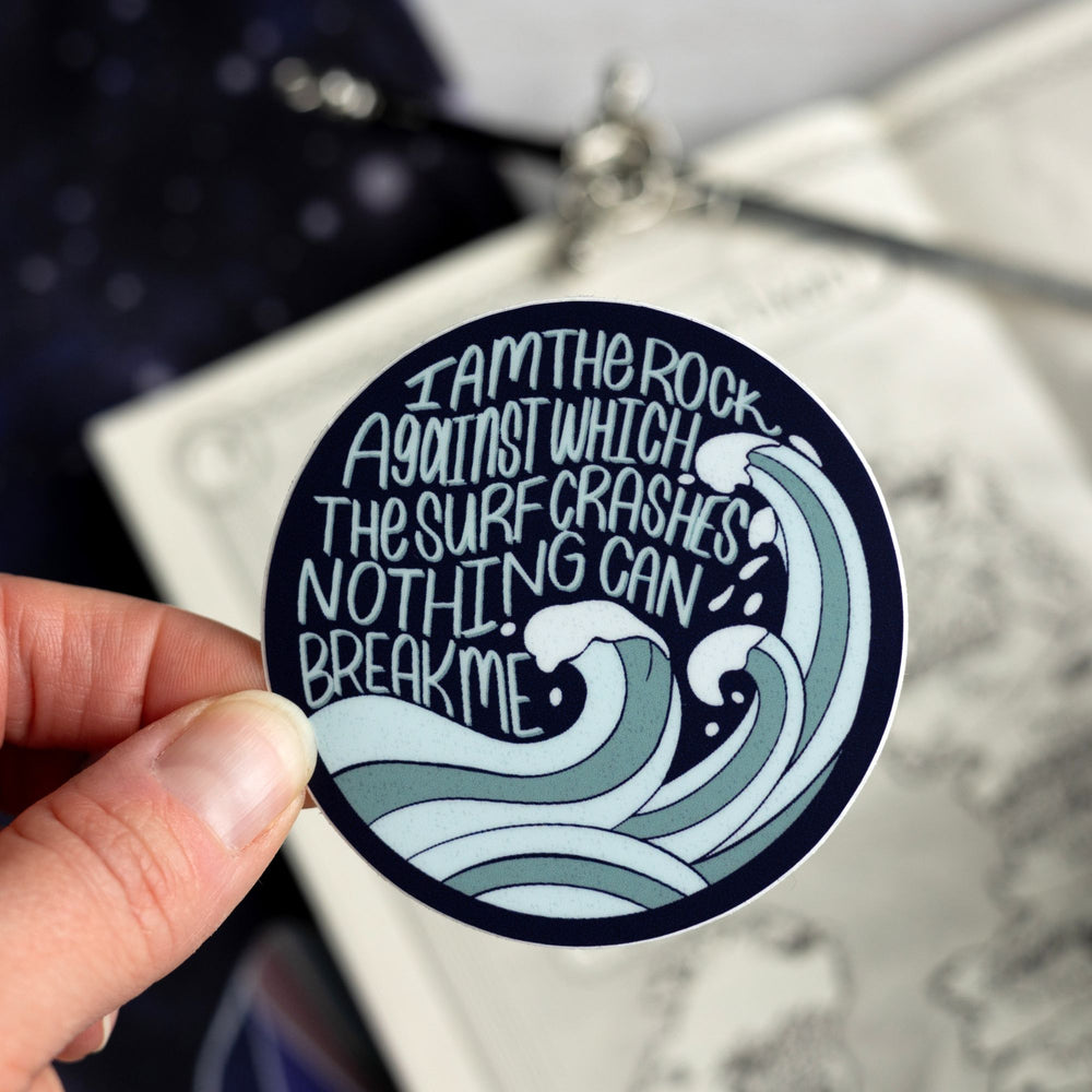 ACOTAR quote sticker ‘I am the rock against which the surf crashed nothing can break me.’ With waves coming up by the words. Held above a map.
