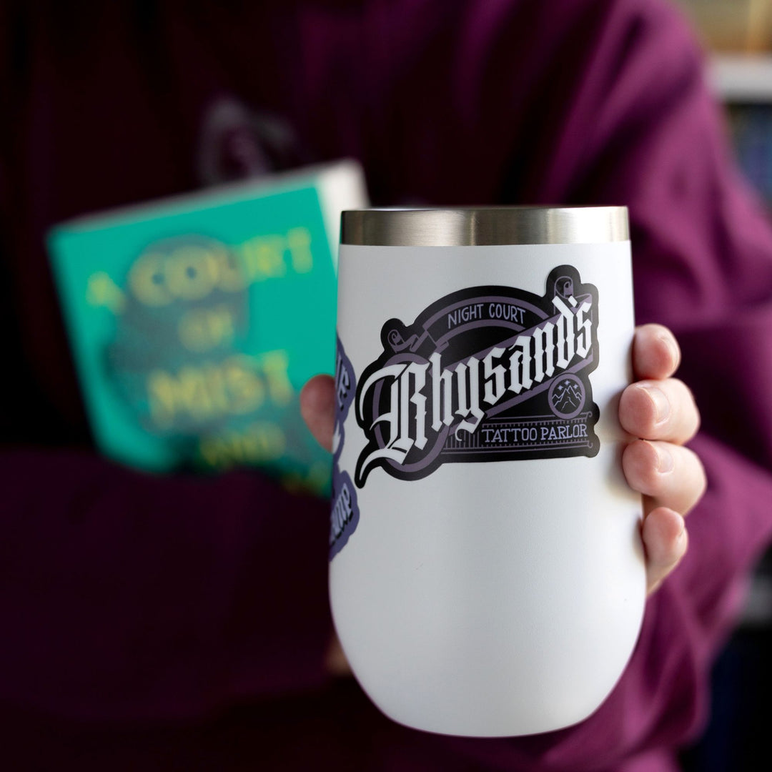  Sticker that looks like a classic style logo and reads ‘Night court, Rhysnad’s Tattoo Parlor’ inspired by ACOTAR. On a white tumbler.

