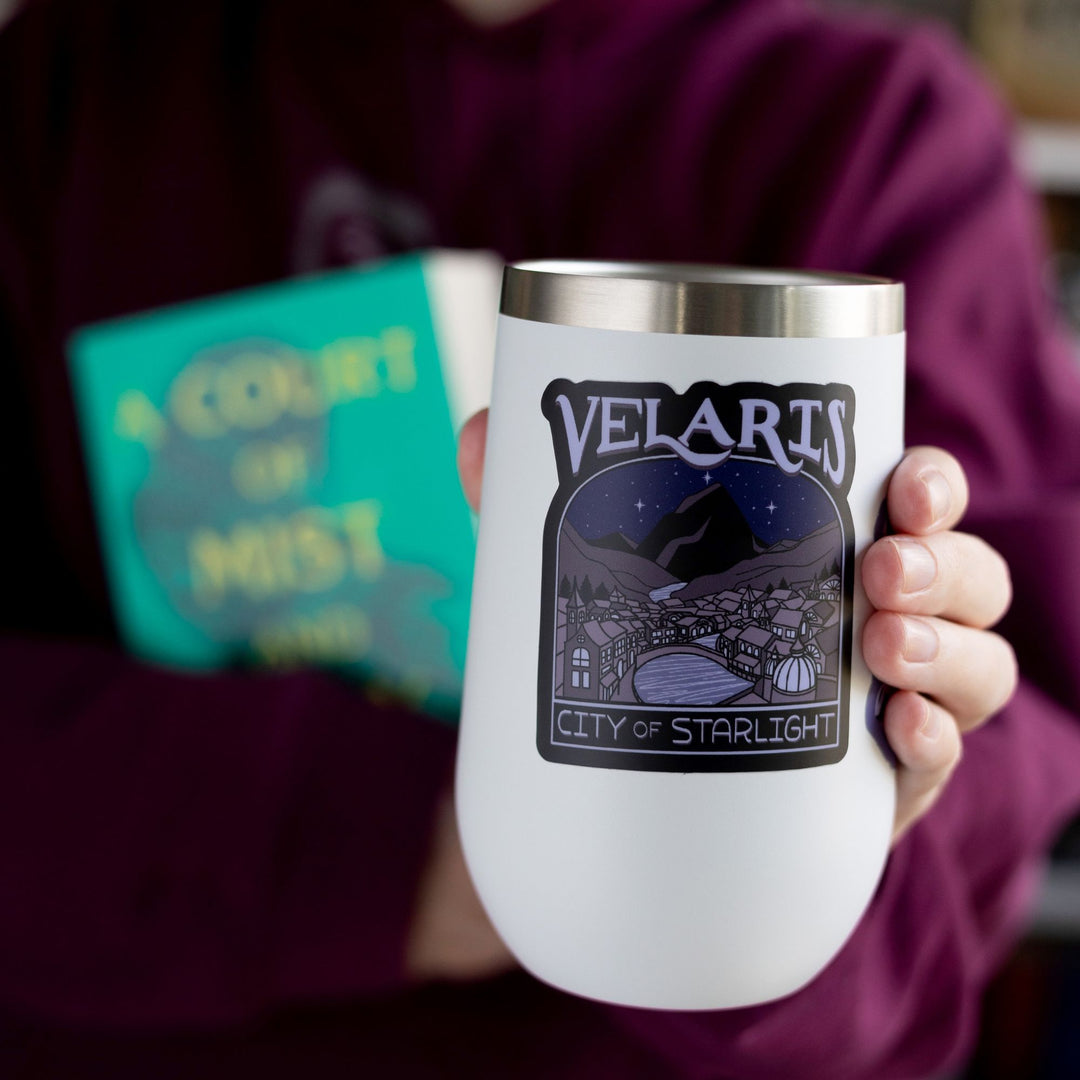 Sticker of Velaris at night, with a river going through it. In purple text: ‘Velaris City of Starlight.’ Inspired by ACOTAR. ‘ City of Starlight’. On a white tumbler.