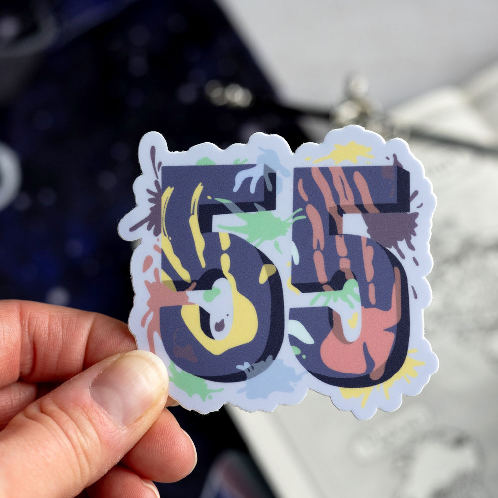  Sticker of a purple number 55 with different paint splatter colors all over it, from ACOTAR. Held above a map.