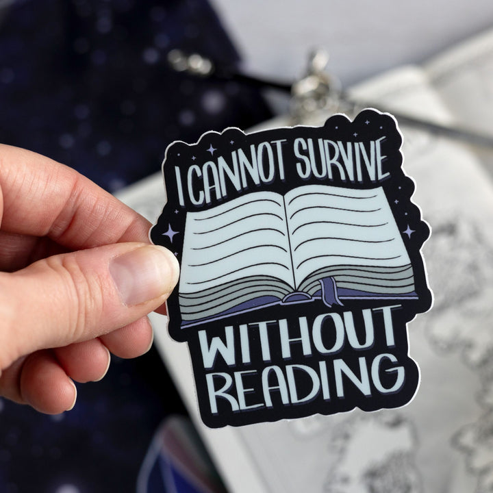  ACOTAR quote sticker ‘I cannot survive without reading’ and an open book with a purple ribbon bookmark. Held above a map.