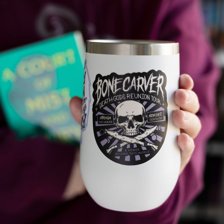 Sticker in a concert poster style with a skull that reads ‘Bonecarver Death Gods Reunion Tour, Stryga the Weaver, Koschei Deathless, a power beyond this world.’ On a white tumbler.
