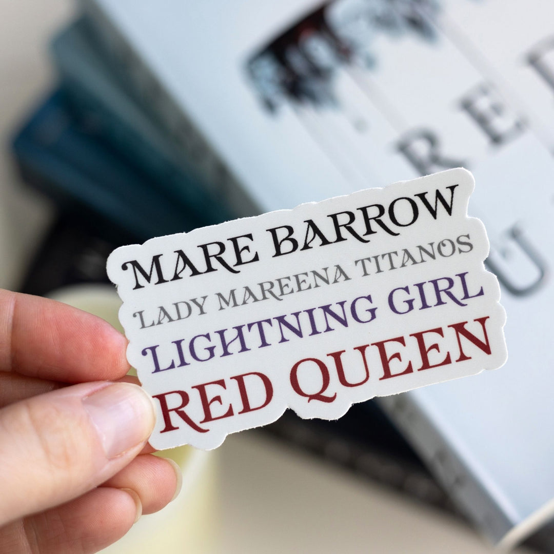 Sticker held over Red Queen. The sticker lists all the names for Mare Barrow in a stack. Text is ‘Mare Barrow, Lady Mareena Titanos, Lightning Girl, Red Queen.’