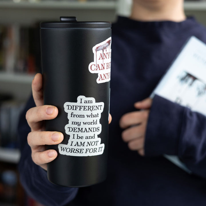 Red Queen quote sticker with black text on a grey background on a white tumbler. Text reads ‘I am different from what my world demands I be and I am not worse for it.’
