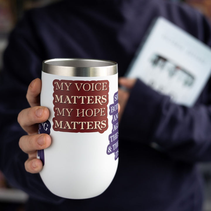 Red Queen quote sticker with tan text on a red background on a white tumbler. Text says ‘My voice matters My hope matters.’