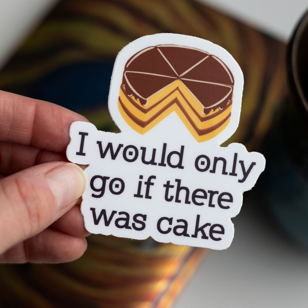 Sticker of the Divergent quote ‘I would only go if there was cake’ with a cake on top of the words, held over the book.