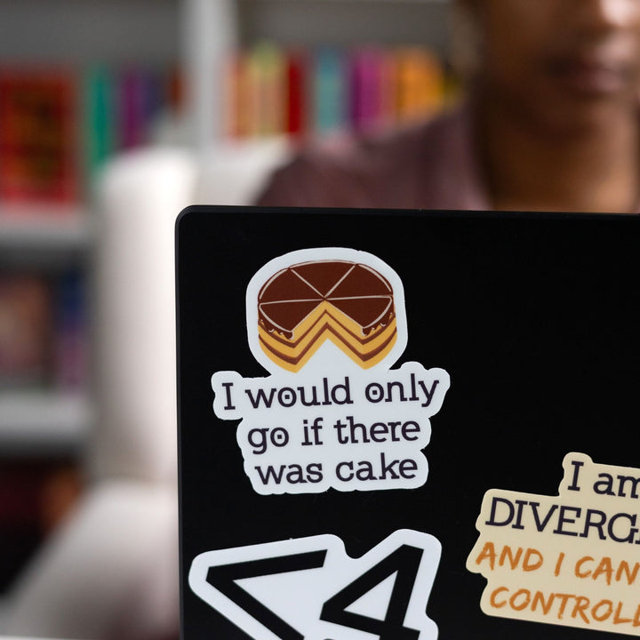 Sticker of the Divergent quote ‘I would only go if there was cake’ with a cake on top of the words, on a black laptop.